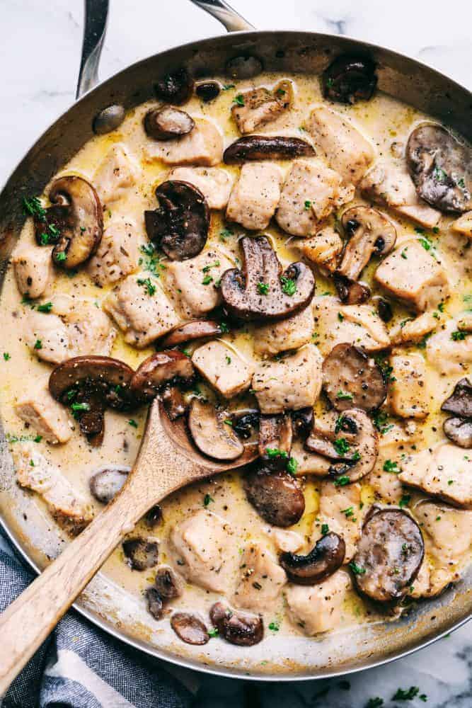 Creamy Garlic Pork Marsala in a frying pan with a wooden spoon. 