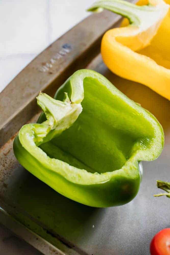 Bell peppers cut in half on a cookie sheet. 