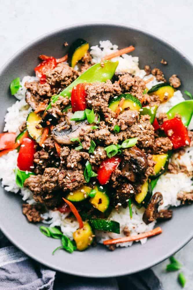 Korean ground beef stir fry over top white rice in a gray bowl. 