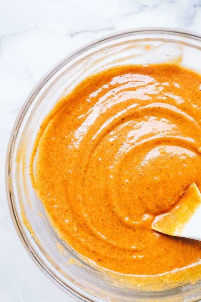 Clear mixing bowl with pumpkin cake batter. 