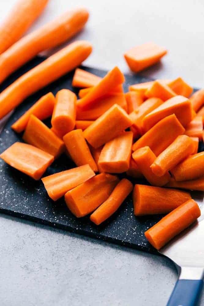 Fresh carrots being cut on a cutting board. 