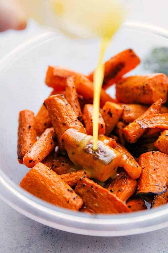 Cooked carrots being with honey orange glaze being drizzled on top. 