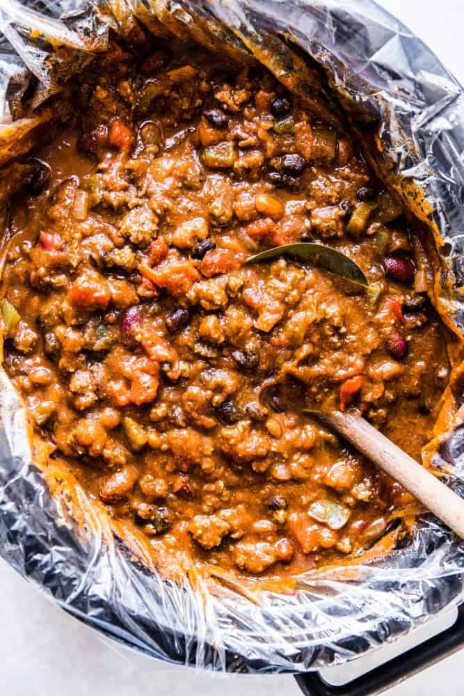 Slow cooker pumpkin chili with a wooden ladle.