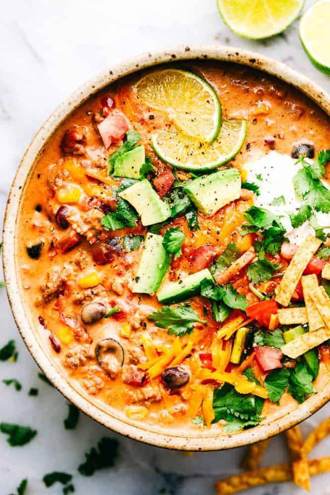 A bowl of Cheesy Taco Soup with fresh sliced limes on top. 