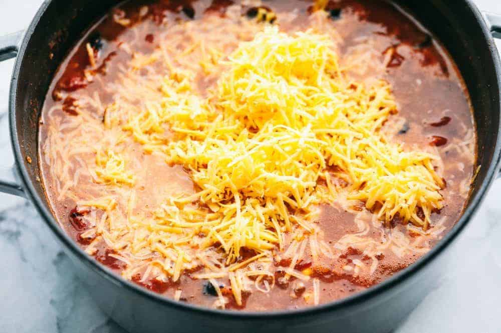 Large pot of Cheesy Taco Soup with freshly grated cheese on top. 