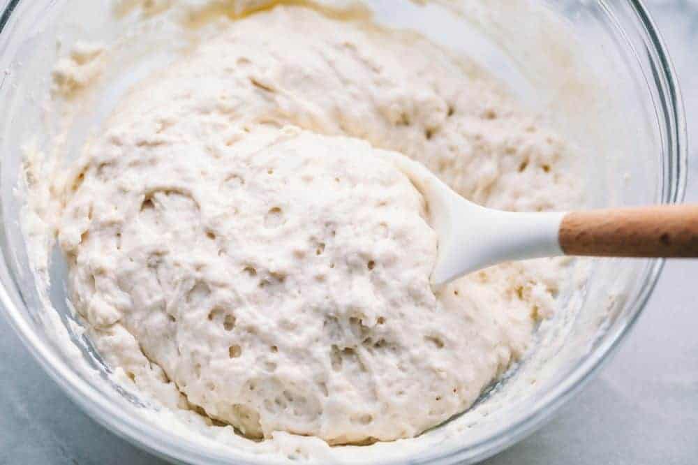 Making the pie for Pecan Pie Cobbler in glass bowl with wooden spoon stirring it. 