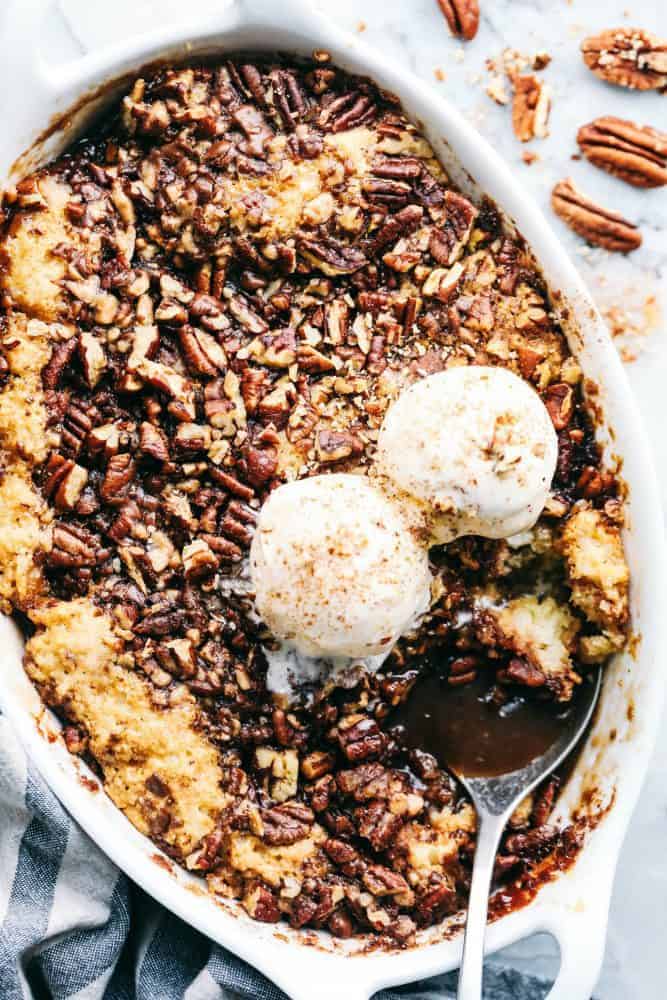 Pecan Pie Cobbler in a white dish with a metal spoon. 