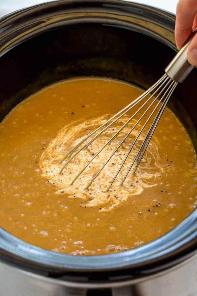 Whisk mixing cream into potato leek soup.