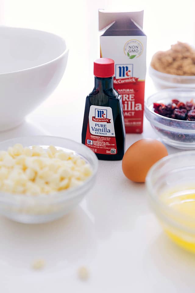 Ingredients to make white chocolate cranberry Blondies separated into individual glass bowls and then McCormick vanilla is centered in the middle of the photo.