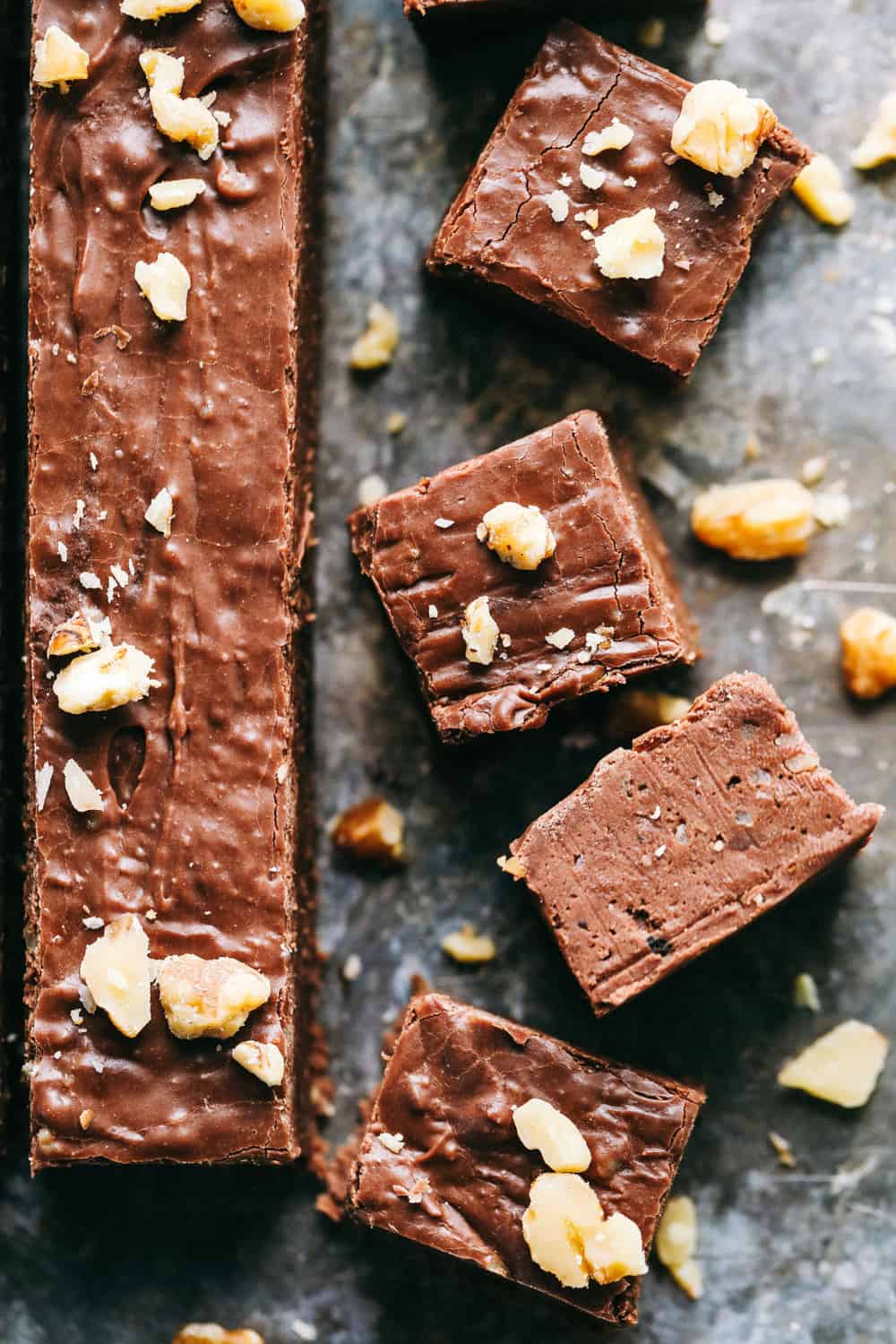 Fantasy fudgeWith the long strip next to it has cut up 1 inch pieces of fudge with walnuts chopped over top and a black countertop.