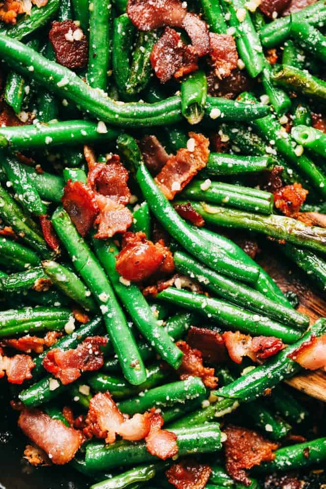 An up close photo of the garlic Parmesan green beans with the chopped up cooked bacon and garnished with Parmesan sprinkles.