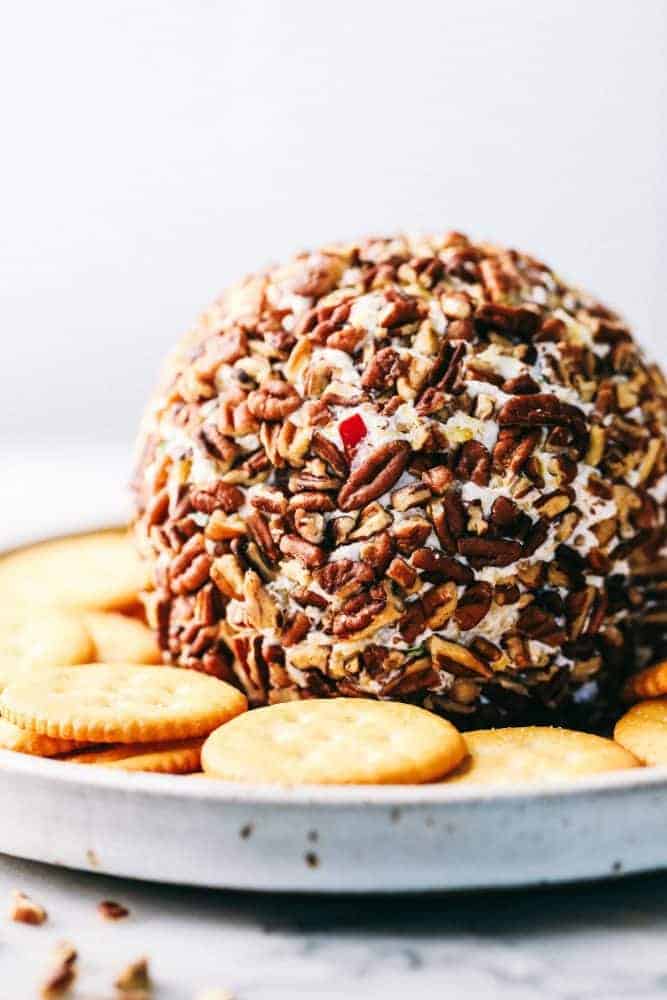 A pineapple cheese ballWith Ritz crackers are around it and white plate.