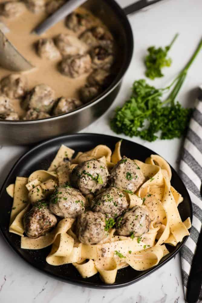 Swedish Meatball Pasta on a black plate garnished with fresh parsley