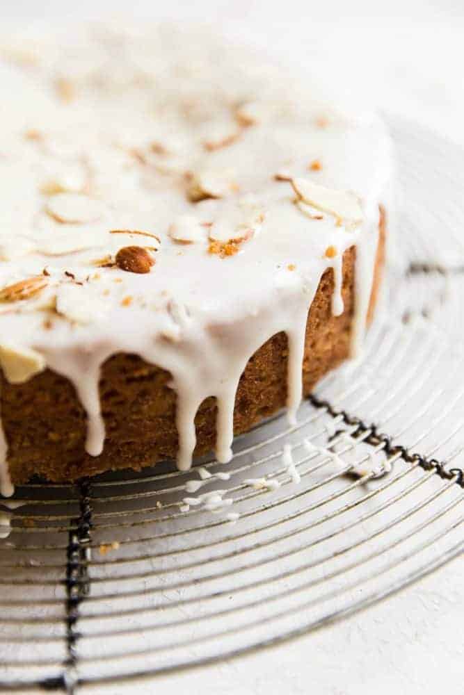 Close up photo of brown butter almond cake on a cooling rack with sliced almonds on top.