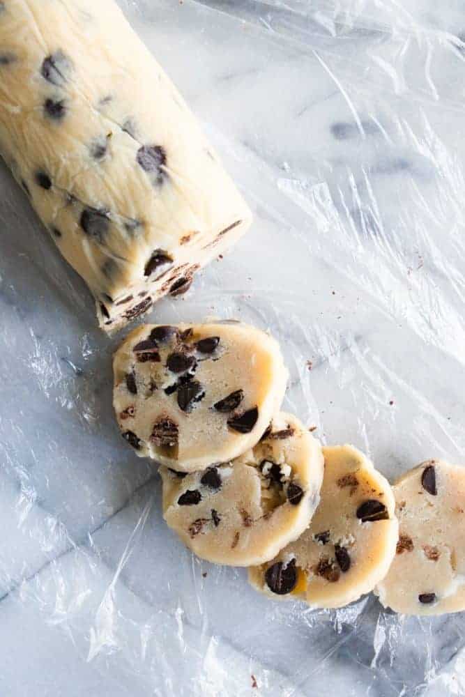 Chocolate chip shortbread cookie dough being sliced and prepared for baking.