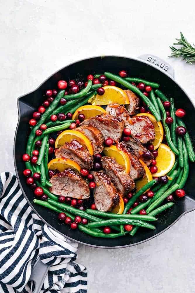 Roasted cranberry orange pork tenderloin with green beans and a black Staub skillet.