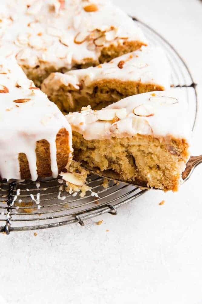 Brown butter almond cake on a cooling rack with the slice being removed.