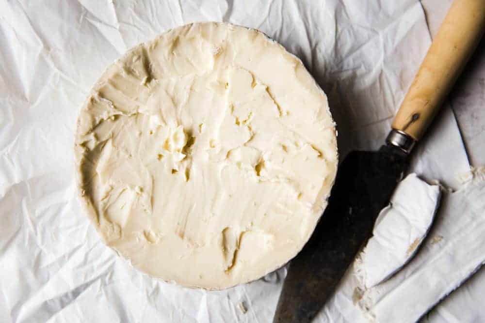 Brie wheel with a metal butter knife next to it. 