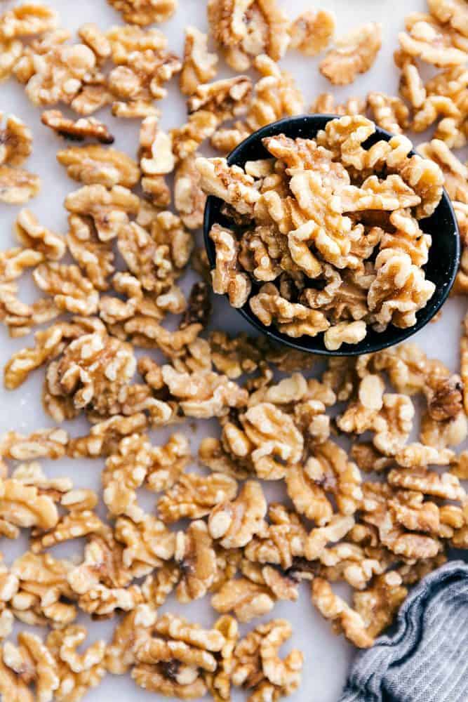 Walnut halves spread out on the table. There are some in a bowl as well.