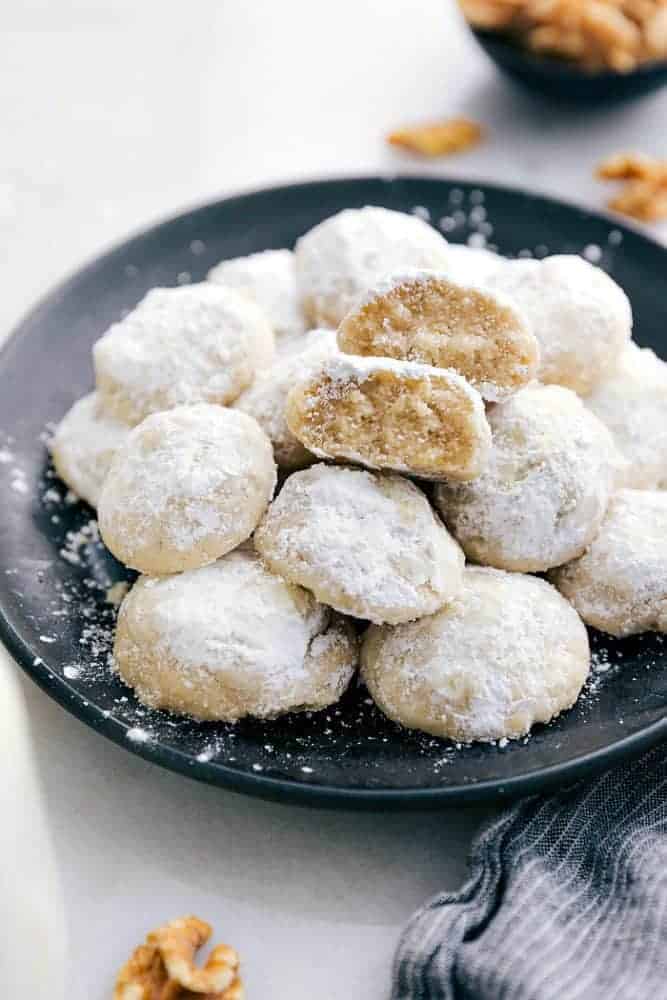 Snow kiss cookies on a black plate.