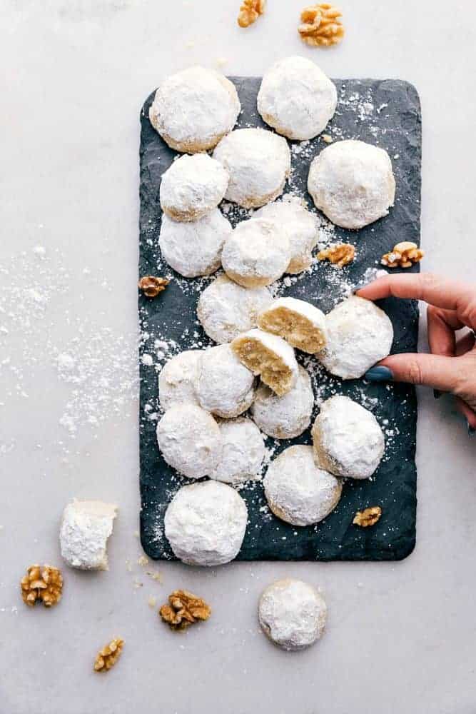 Snow kiss cookies on a black cutting board.