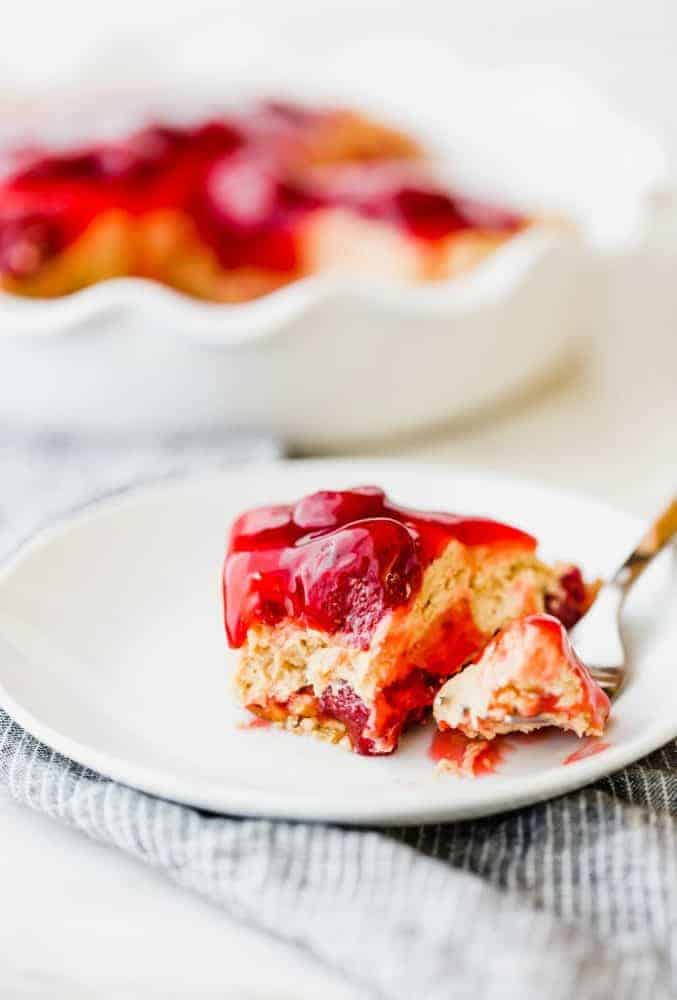 One slice of strawberry peanut butter pie on a white plate with a metal fork.