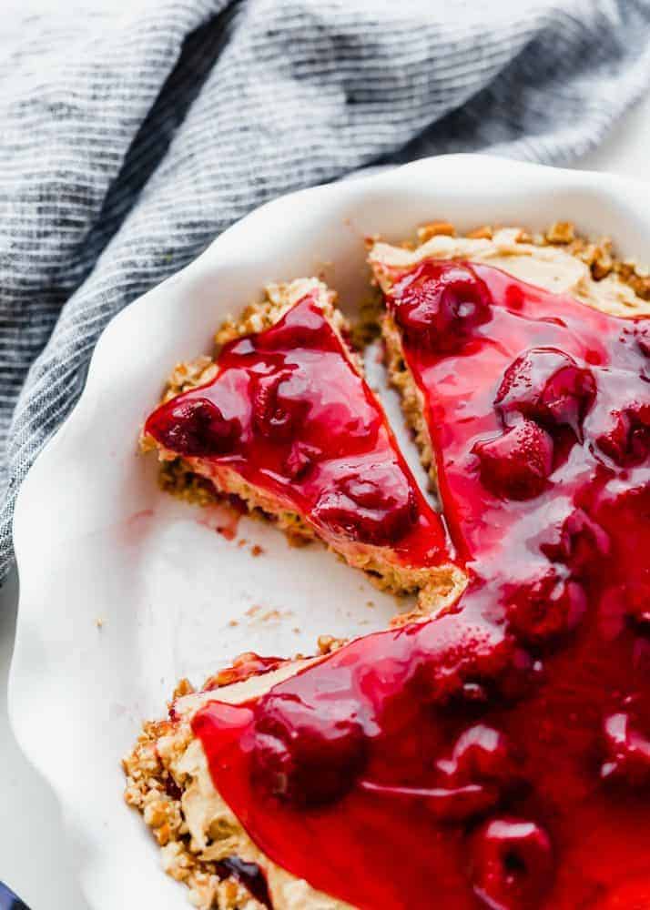 Strawberry peanut butter pie in a white pie pan with a slice being removed.