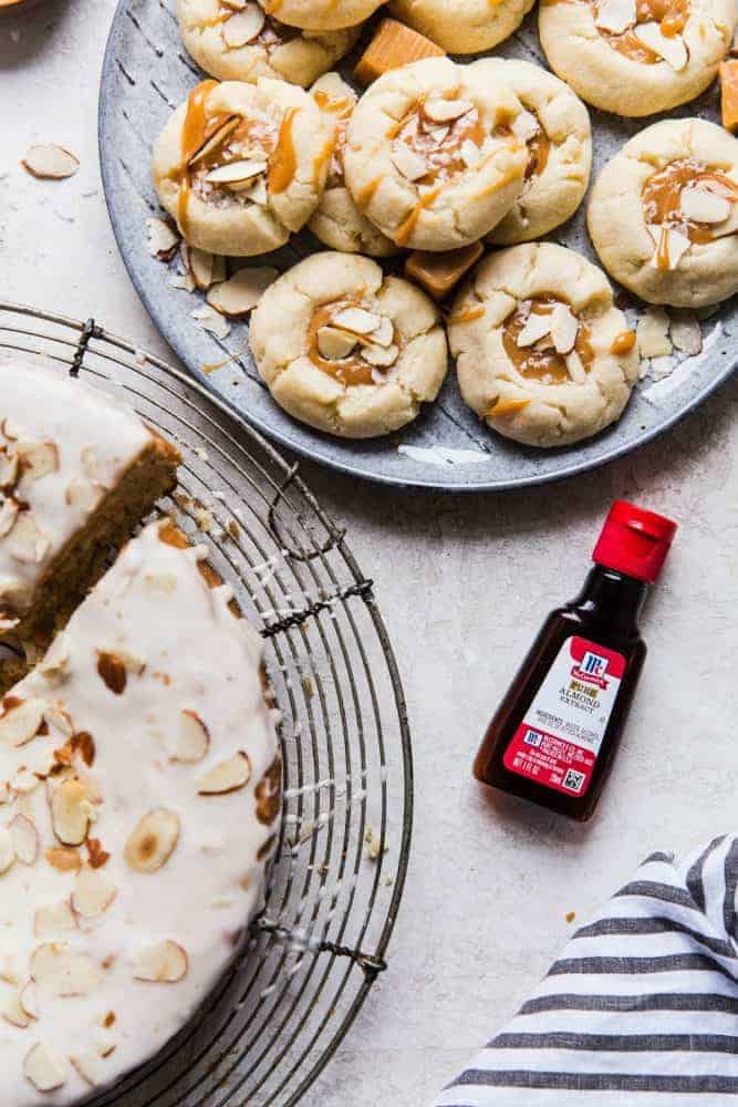 Almond thumbprint cookies on a gray plate with a bottle of McCormick almond extract on the side.