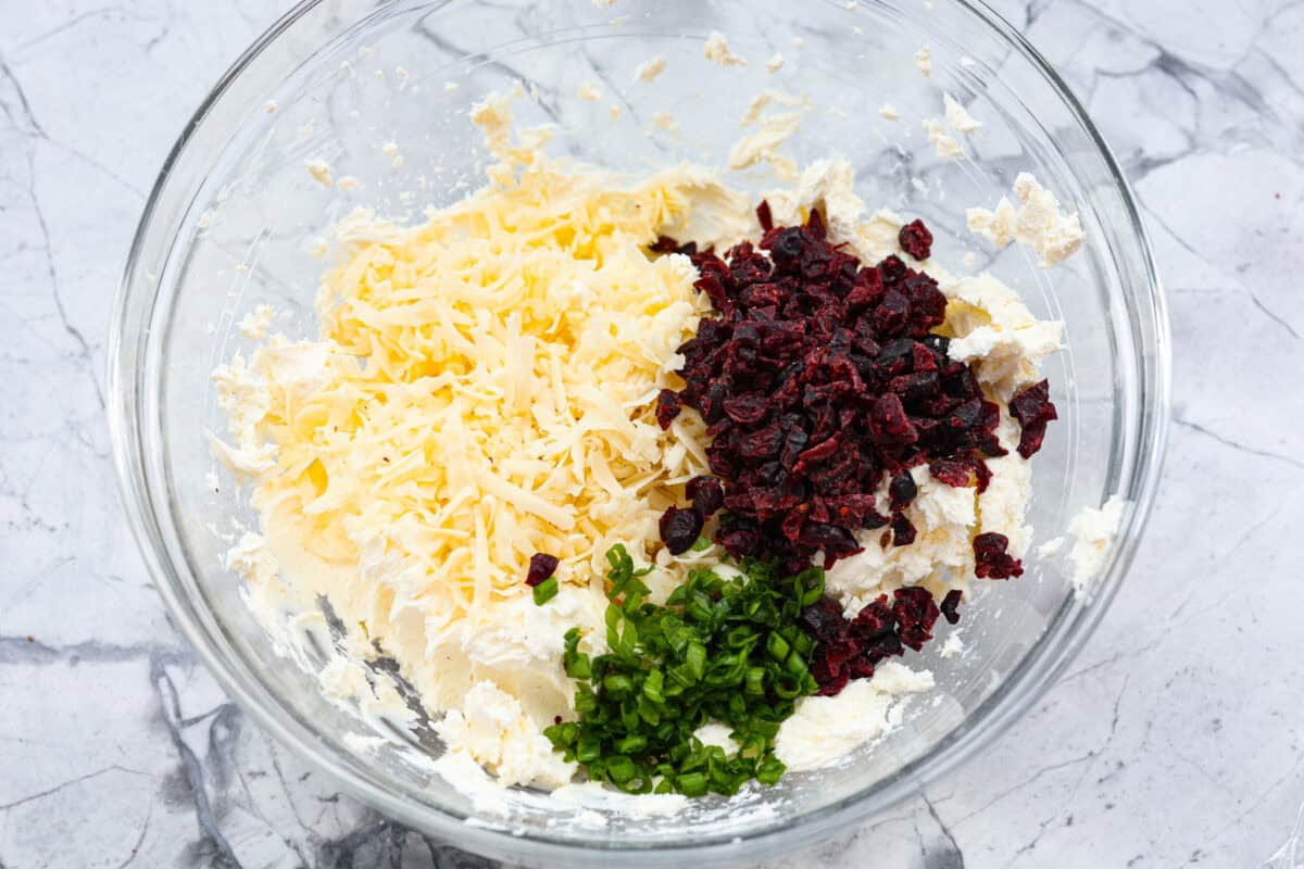 Second photo of the shredded cheese, cranberries and green onions added to the bowl.