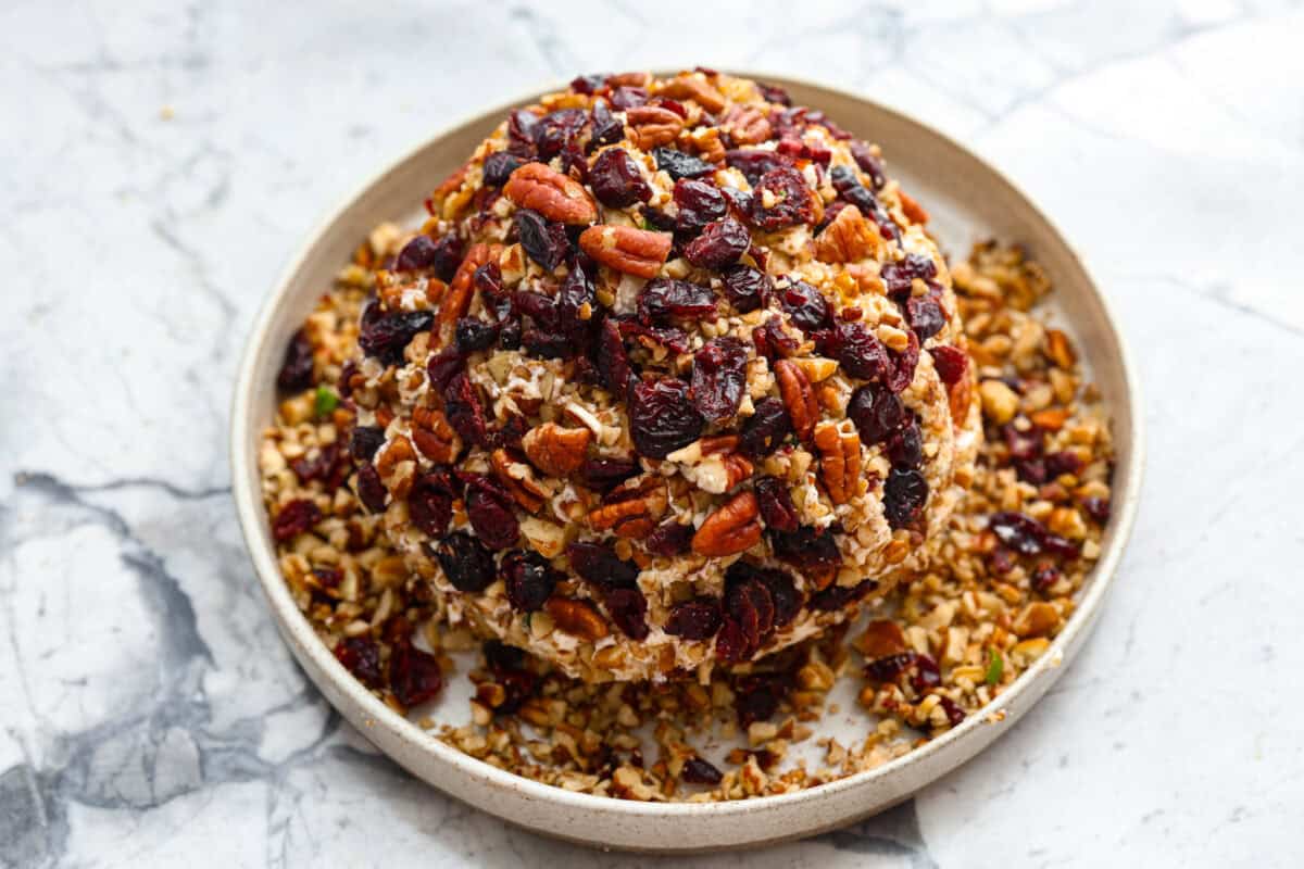 Sixth photo of the remaining cranberries and pecans being placed on the cheese ball.