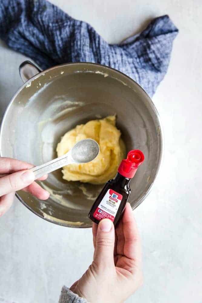 Adding McCormick almond extract to cookie batter.