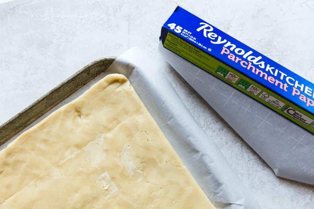 Uncooked shortbread cookies on a cookie sheet with Reynolds Kitchen parchment paper on the side.