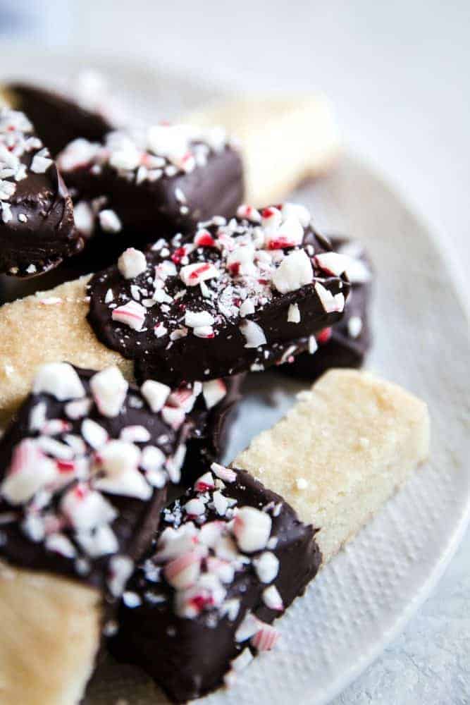 Close up photo of chocolate peppermint dip shortbread cookies on a white plate.