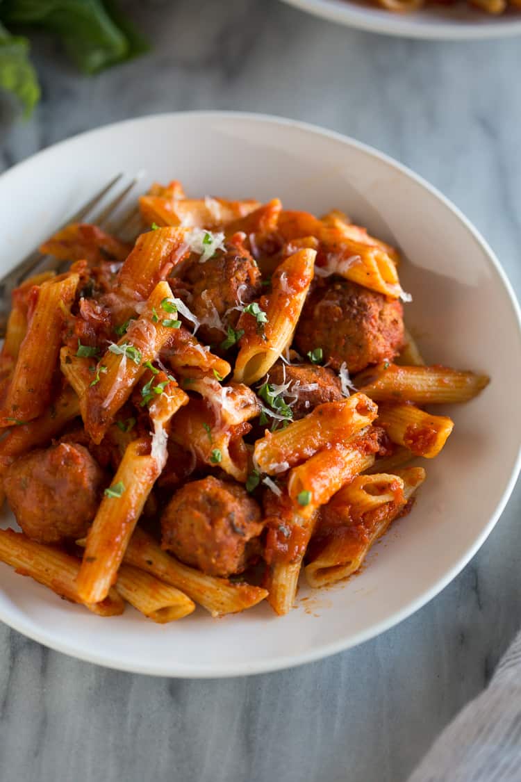 A white bowl of insta pot pasta with meatballs.