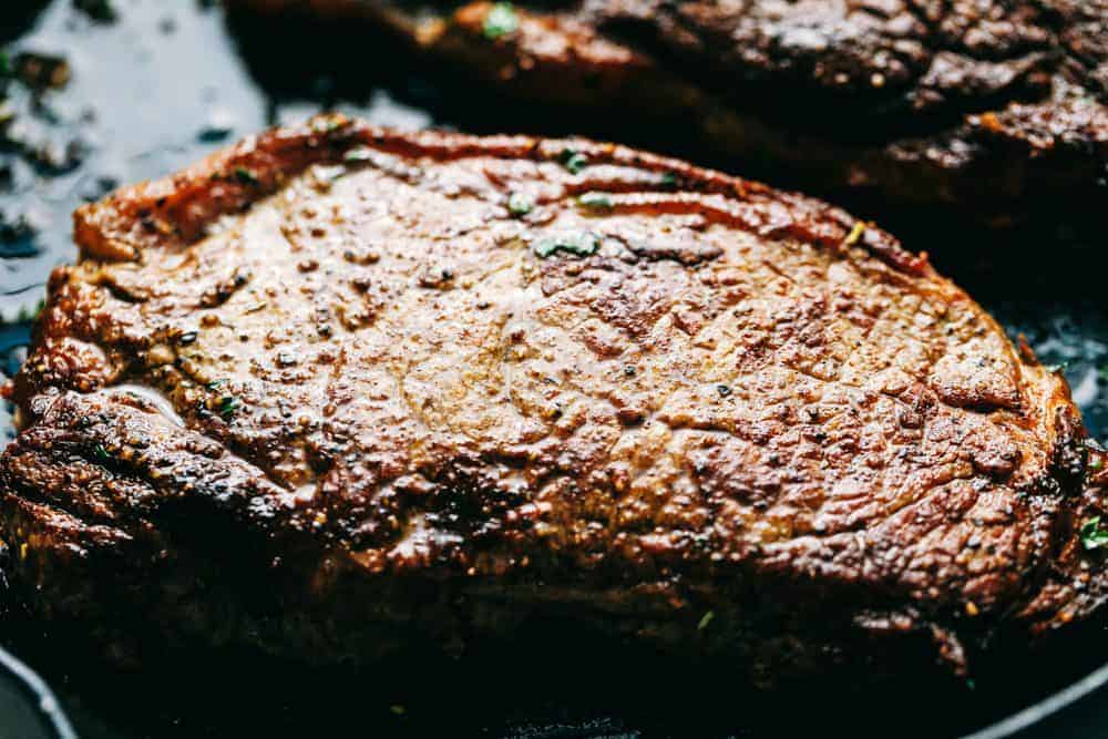 Steak cooking in a cast iron pan.