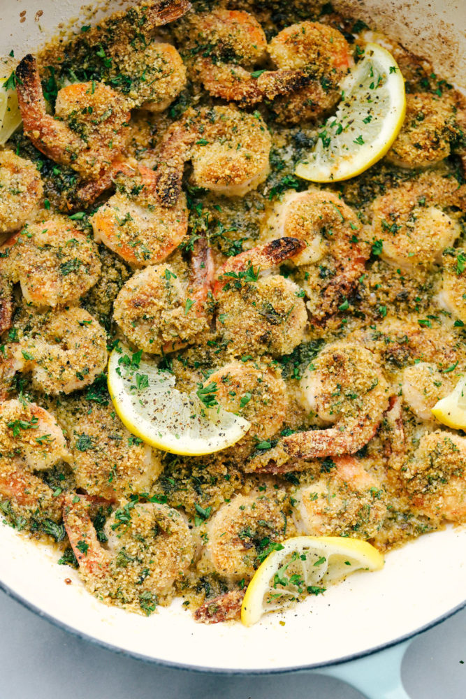 Lemon garlic shrimp in a skillet with lemon wedges. 