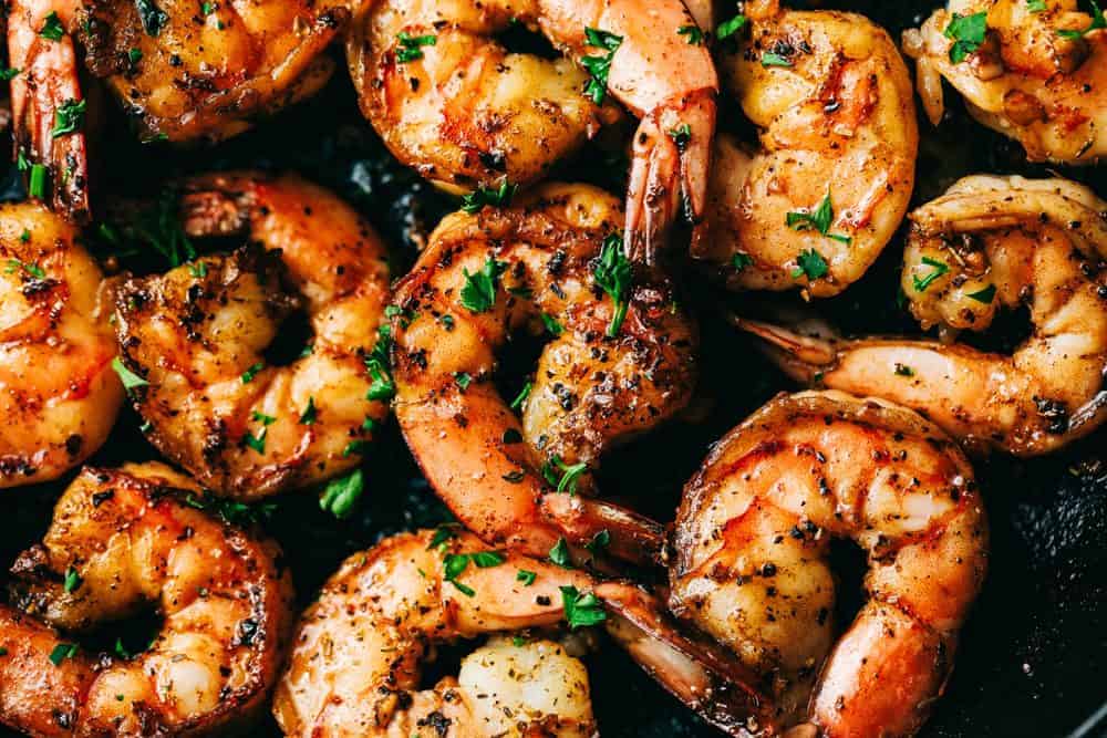 Shrimp cooking in a pan with seasonings.