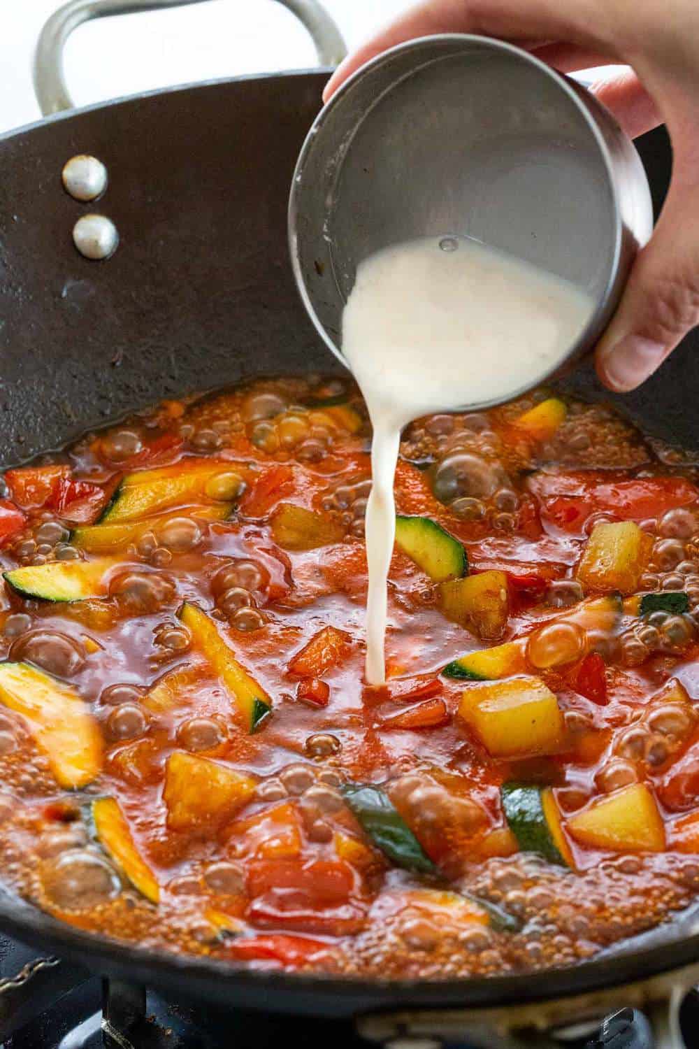 cornstarch being poured into a wok to make sauce