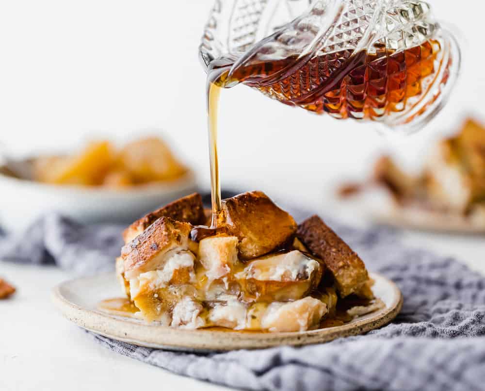 Pouring syrup on french toast casserole on a plate.