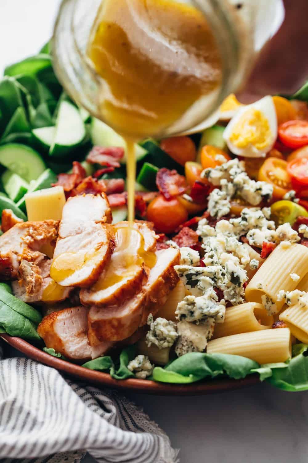 Pouring dressing on pasta cobb salad