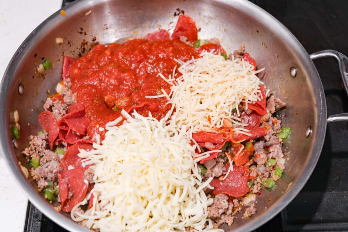 Overhead shot of meat and veggie mixture with sauce and cheeses. 