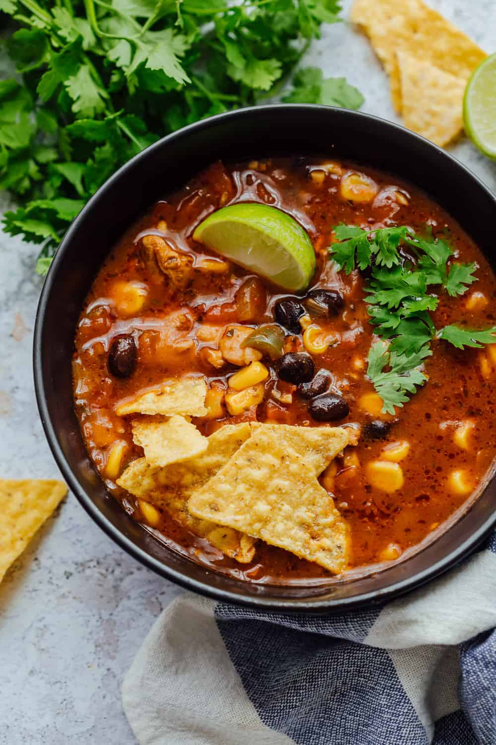 Chicken tortilla soup served in a black bowl with toppings