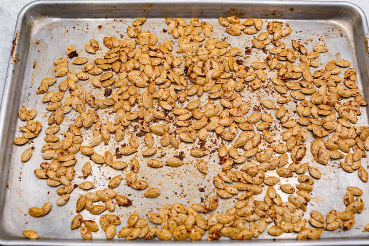 Overhead shot of pumpkin seeds drenched in oil and seasonings. 