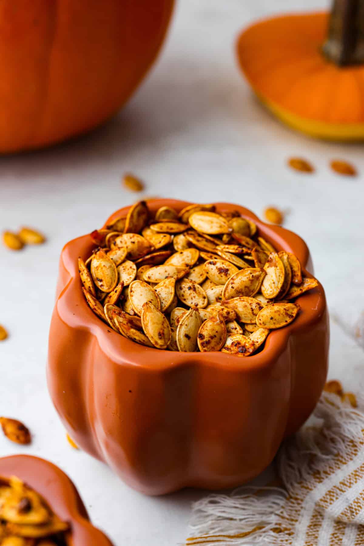 Angle shot of roasted pumpkin seeds in a cute pumpkin container.