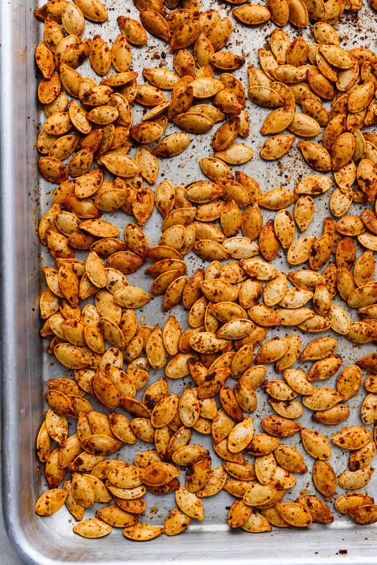 Overhead shot of roasted pumpkin seeds on a pan. 