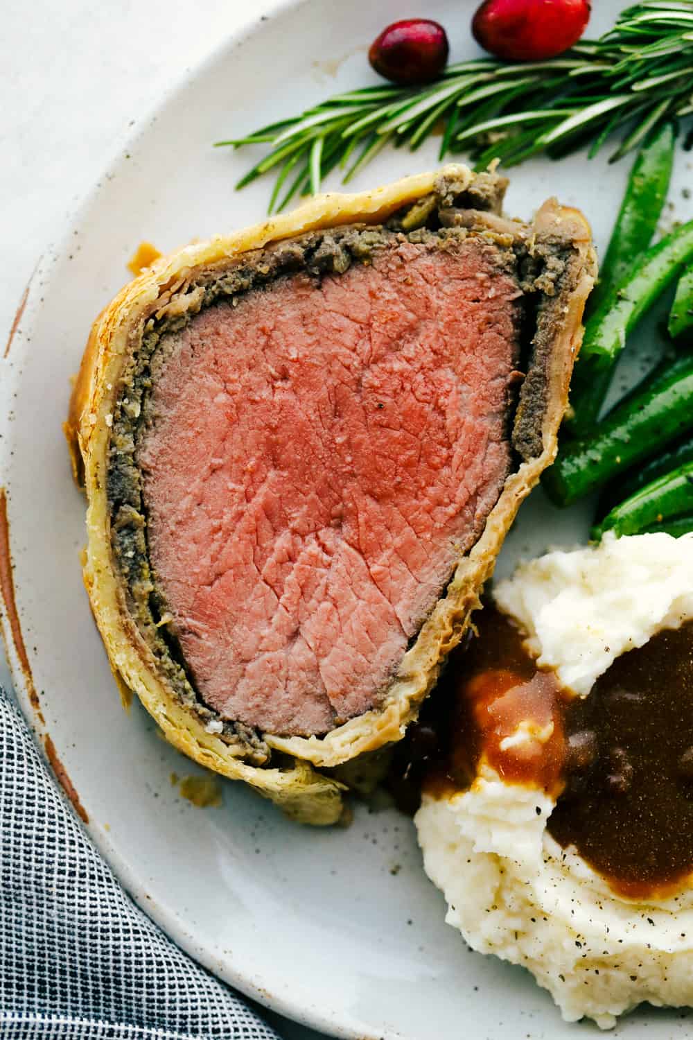 Beef Wellington sliced onto a plate with mashed potatoes and green beans