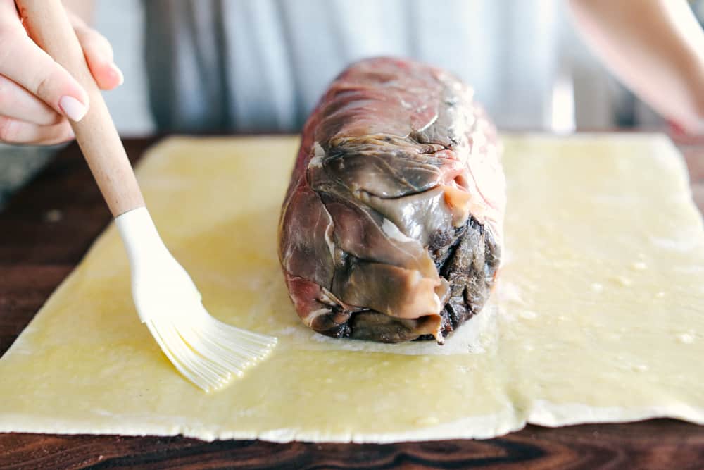 Side shot of someone brushing butter on to the pastry. 