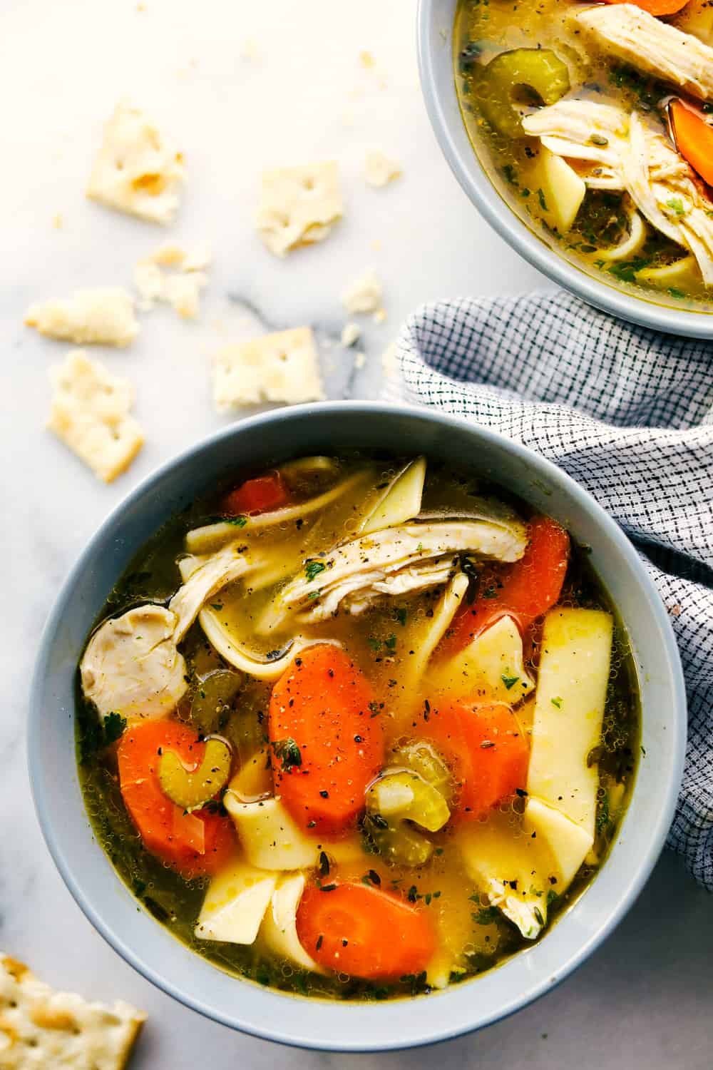 Close view of chicken noodle soup in a gray bowl.