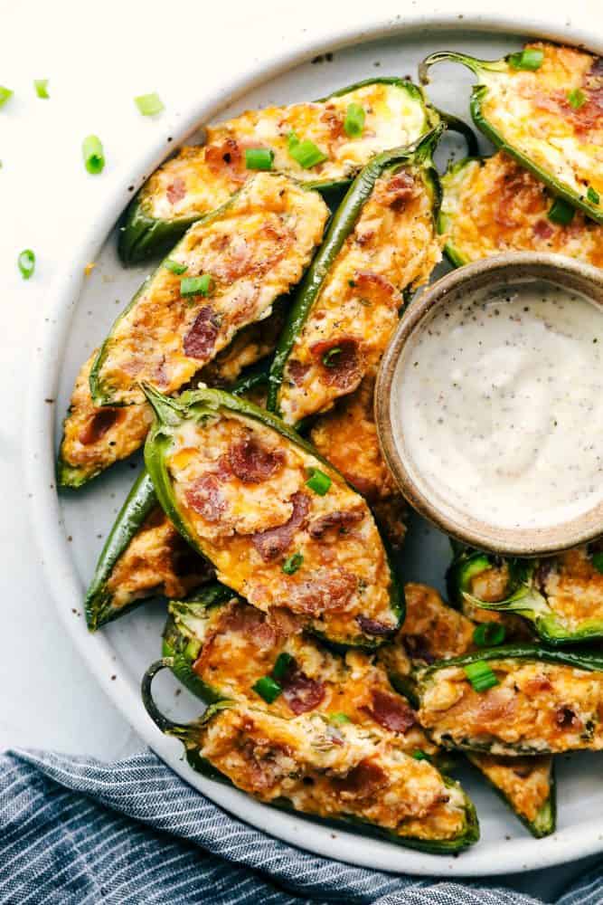 A platter of jalapeño poppers with some dip. 