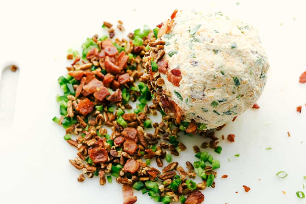 Rolling the cheese ball in the bacon, pecans, peppers, and onions.